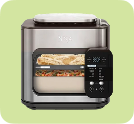 Air Fryer with food and light on on green background.