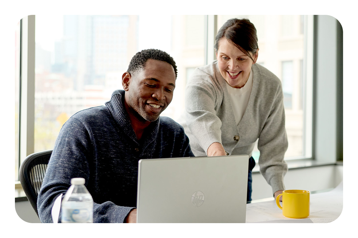 Two people in an office collaborating over a laptop.