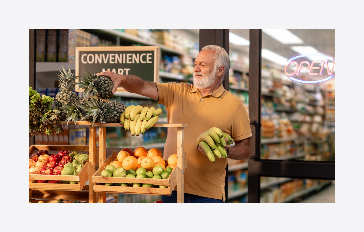 A man stacks fruit at a grocery store.