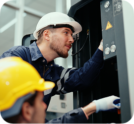 A pair of electricians working on an electrical panel.