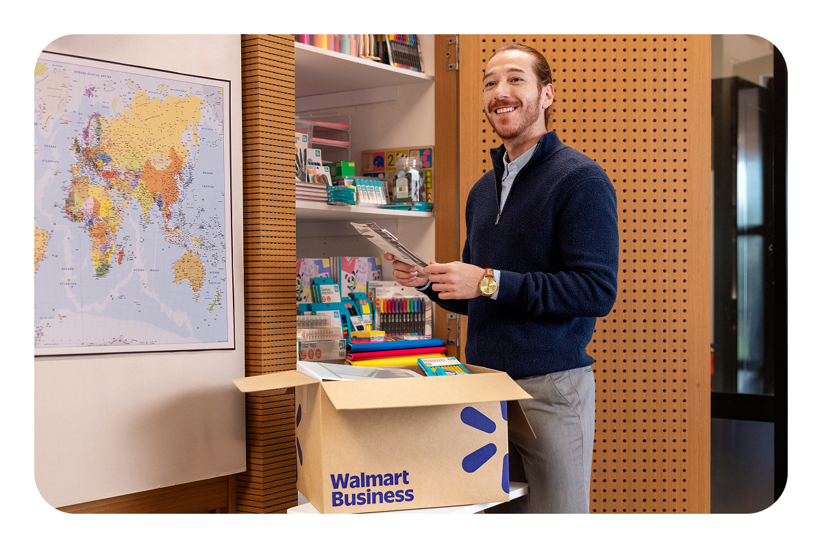A teacher unpacking a Walmart Business box full of school supplies.