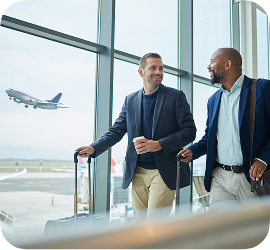 Two men in blazers with roller bags at an airport
